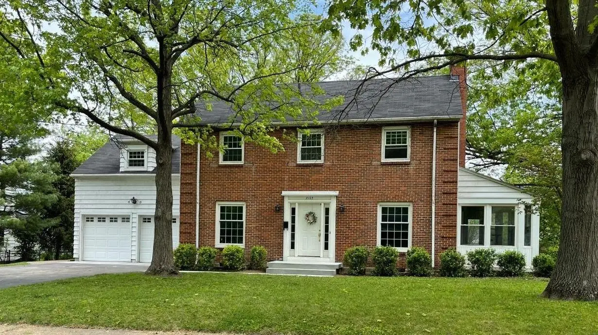 Two-story brick colonial home with a white front door and attached garage